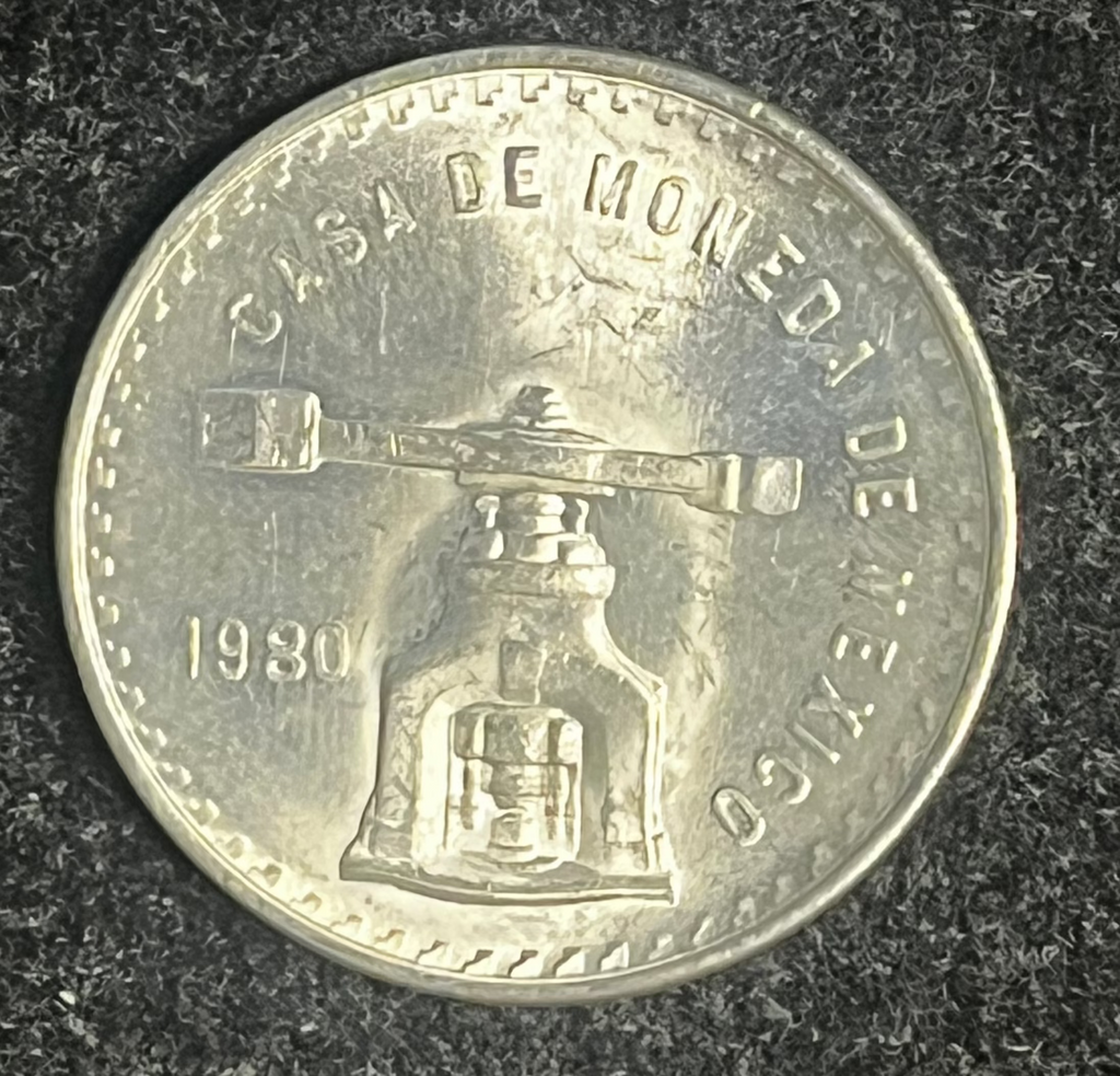 Silver coin with embossed design and text on a dark textured surface