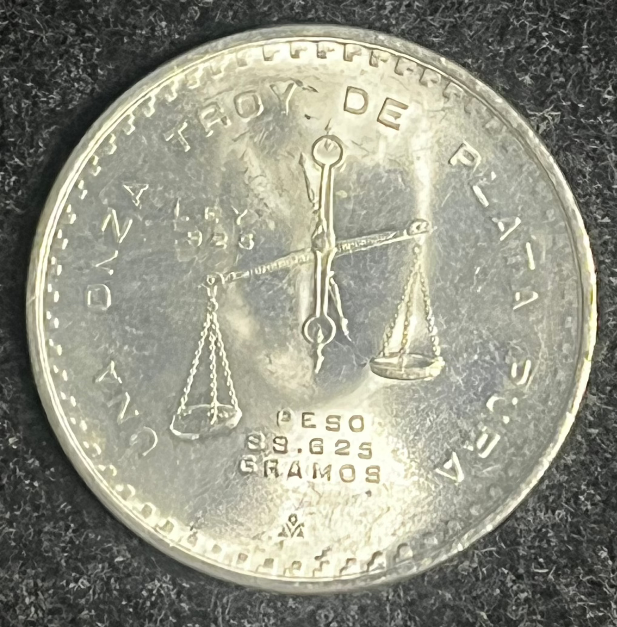 Silver coin with embossed design on a dark textured background