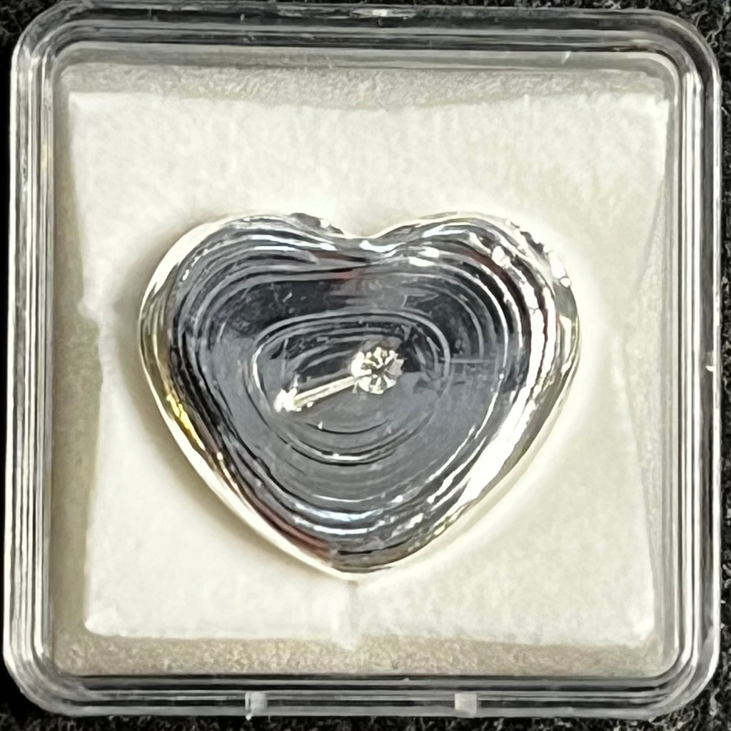 Heart-shaped crystal in a clear display case on a dark textured background