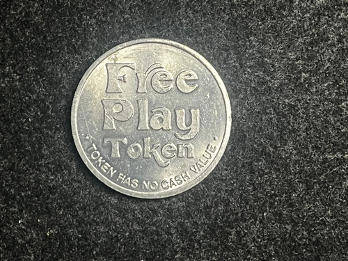 Silver token with 'Free Play Token' text on a dark textured background